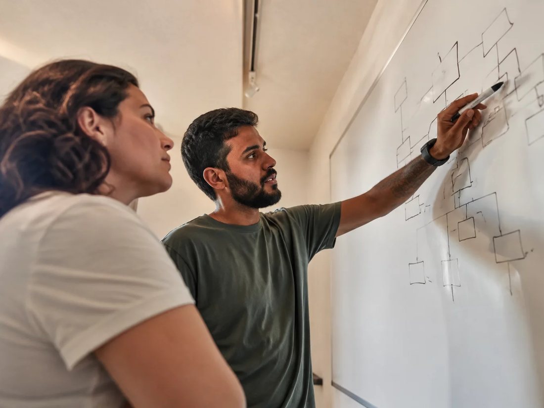 Quem conduz aponta para o esquema de um argumento no quadro branco enquanto um inscrito acompanha